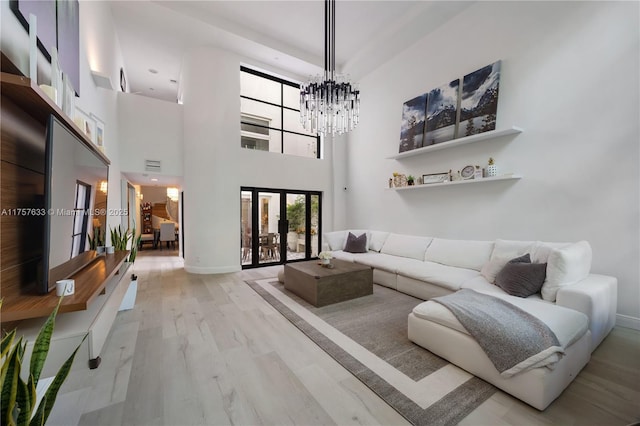 living area with a notable chandelier, visible vents, baseboards, light wood-style floors, and french doors