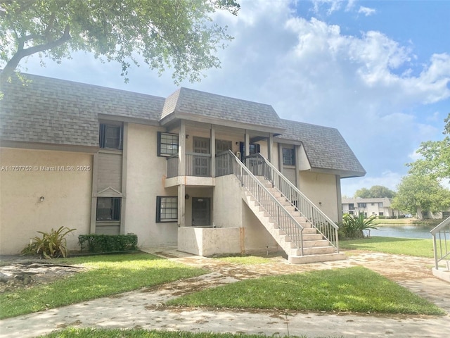 exterior space with stucco siding, roof with shingles, mansard roof, and stairs