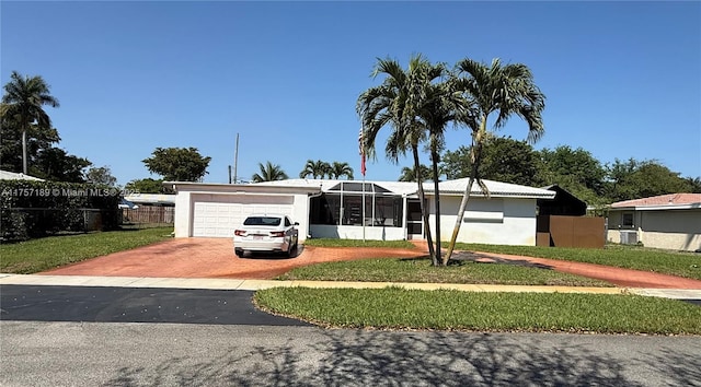 view of front of house featuring an attached garage, fence, decorative driveway, a front lawn, and stucco siding