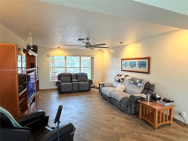 living room featuring visible vents, a textured ceiling, a ceiling fan, and wood finished floors