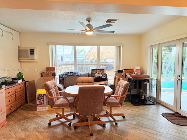 dining space with a healthy amount of sunlight, visible vents, light wood finished floors, and a wall mounted AC