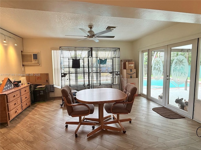 dining area with a ceiling fan, wood tiled floor, a wall mounted AC, french doors, and a textured ceiling
