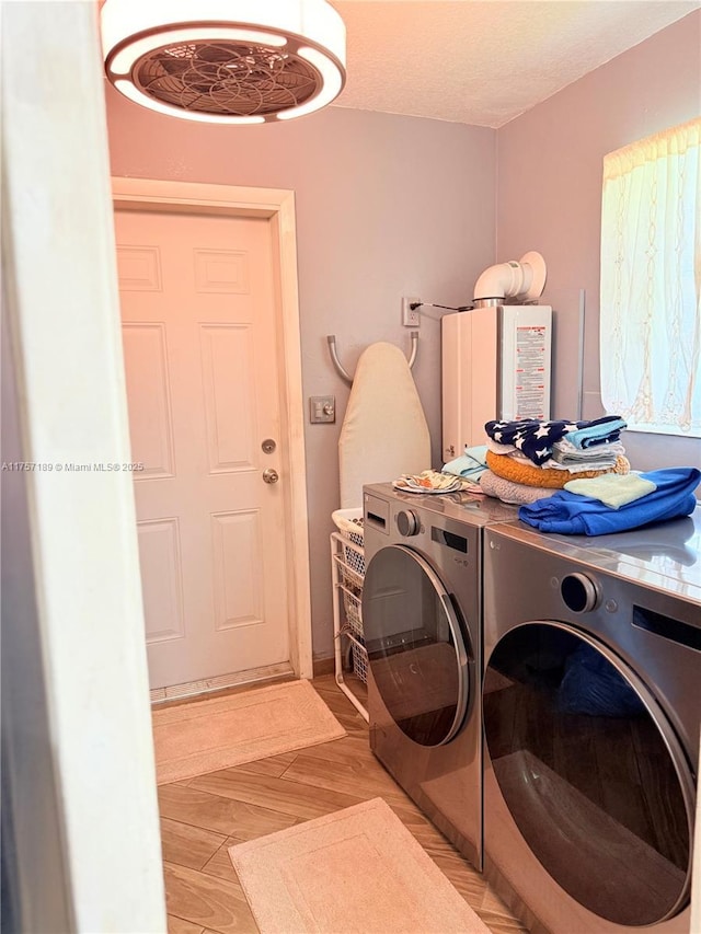 laundry area with laundry area, a textured ceiling, light wood-style floors, and washer and dryer