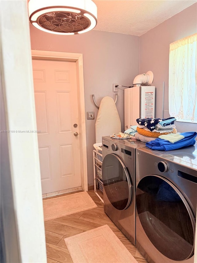 laundry room with laundry area, washing machine and dryer, light wood-type flooring, and a textured ceiling