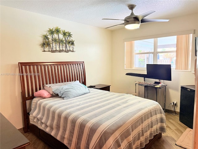 bedroom with a textured ceiling, ceiling fan, and wood finished floors