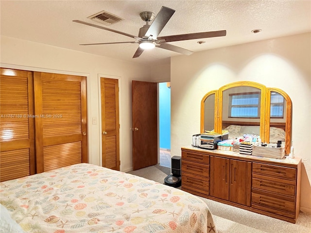 bedroom with light carpet, visible vents, a textured ceiling, and a ceiling fan