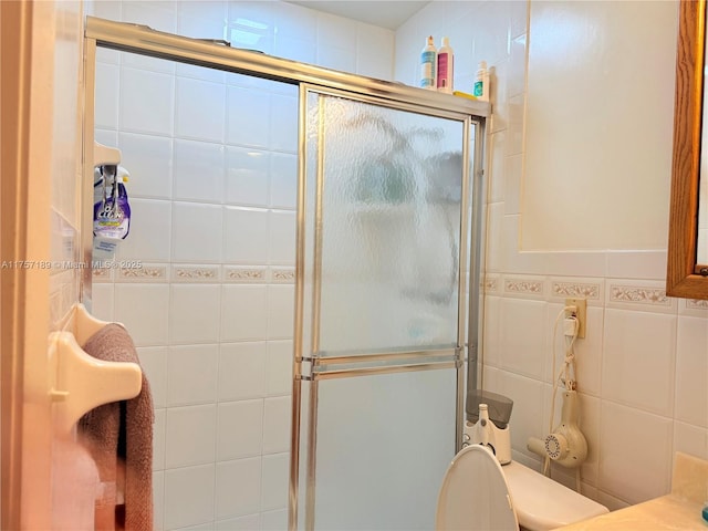 full bathroom with a shower stall, tile walls, and toilet