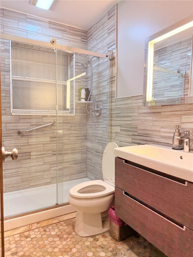 bathroom with toilet, vanity, tile walls, a shower stall, and decorative backsplash