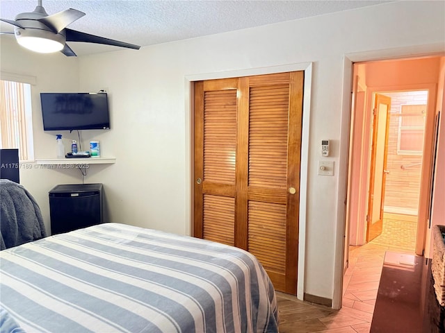 bedroom featuring ceiling fan, wood finished floors, a closet, refrigerator, and a textured ceiling