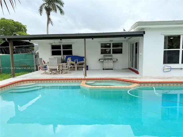 view of pool with grilling area, a patio area, fence, and a pool with connected hot tub