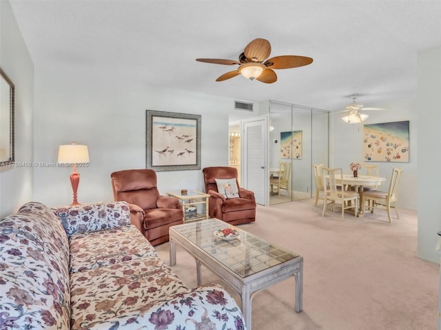 living area with carpet, visible vents, and ceiling fan