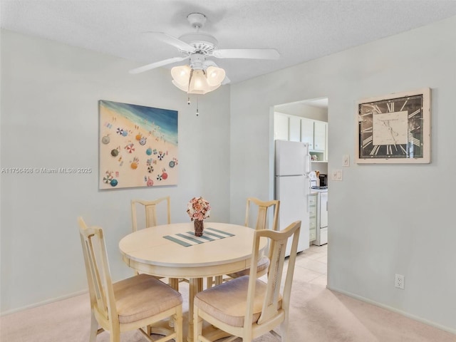 dining space with light carpet, ceiling fan, and a textured ceiling