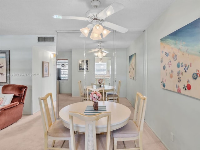 dining area featuring light carpet, visible vents, and a ceiling fan