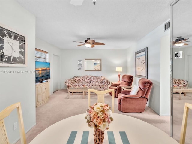 carpeted living room featuring ceiling fan, visible vents, and a textured ceiling