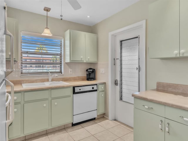 kitchen featuring green cabinets, white dishwasher, light countertops, pendant lighting, and a sink