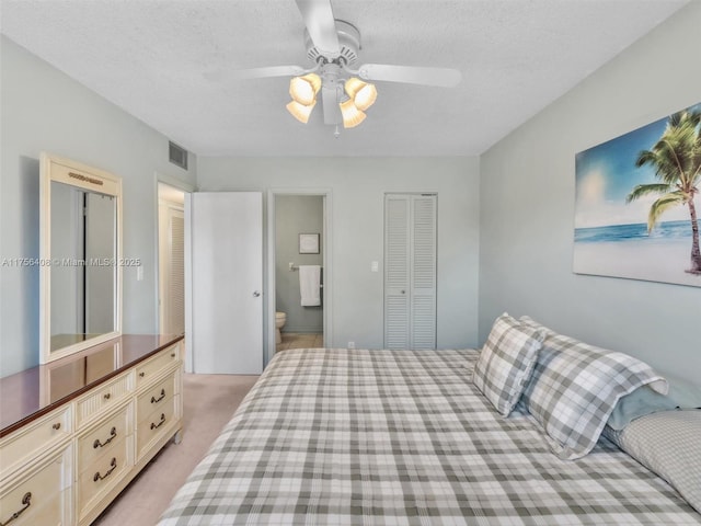 bedroom featuring a textured ceiling, ensuite bathroom, light carpet, visible vents, and a closet