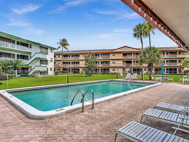 pool featuring a patio area, a yard, and fence