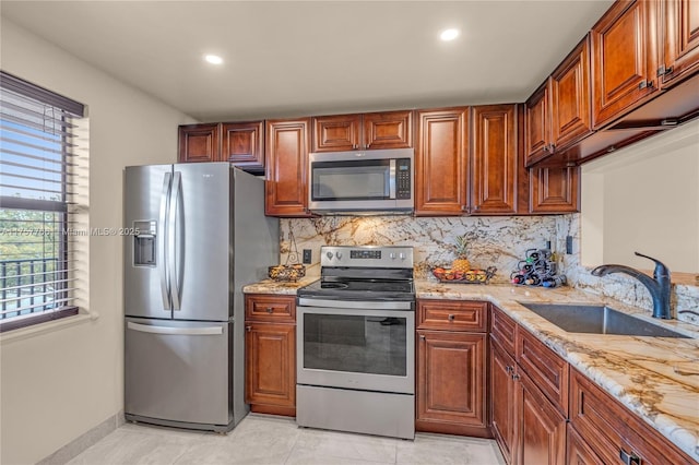 kitchen with light stone countertops, tasteful backsplash, stainless steel appliances, and a sink