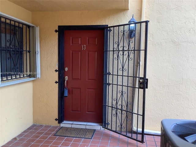 property entrance featuring cooling unit and stucco siding