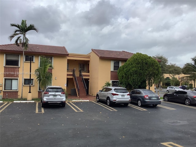 view of building exterior with uncovered parking and stairway