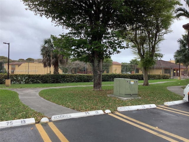 view of home's community featuring uncovered parking, fence, and a lawn