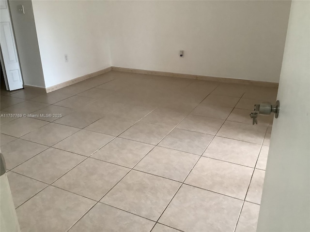 spare room featuring light tile patterned flooring and baseboards