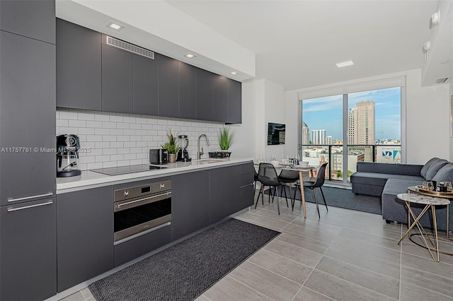 kitchen with decorative backsplash, a sink, modern cabinets, oven, and black electric cooktop