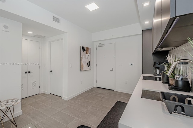 kitchen with light tile patterned flooring, visible vents, baseboards, light countertops, and backsplash