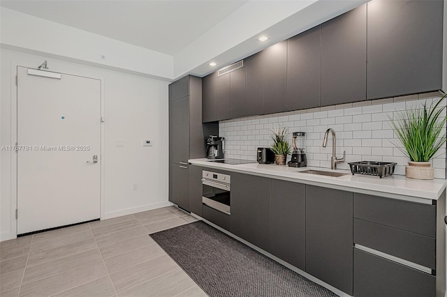 kitchen featuring wall oven, tasteful backsplash, visible vents, black electric cooktop, and a sink