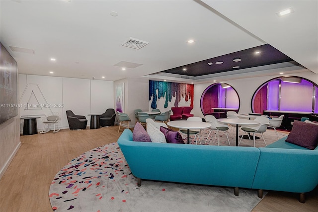 interior space with a tray ceiling, visible vents, recessed lighting, and wood finished floors