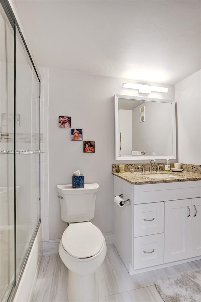 bathroom featuring toilet, shower / bath combination with glass door, and vanity