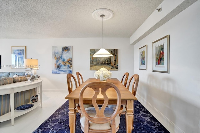 dining area featuring a textured ceiling, tile patterned flooring, and baseboards