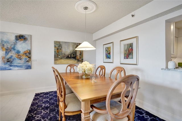 dining room featuring a textured ceiling and baseboards