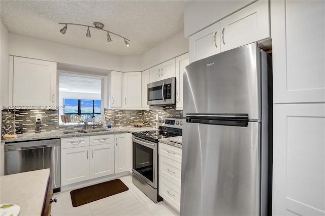 kitchen featuring stainless steel appliances, tasteful backsplash, a sink, and white cabinetry