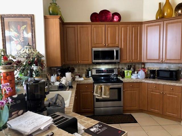 kitchen featuring stainless steel appliances, backsplash, tile countertops, and light tile patterned floors