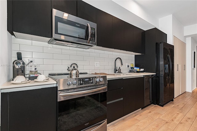 kitchen with a sink, modern cabinets, appliances with stainless steel finishes, and dark cabinetry