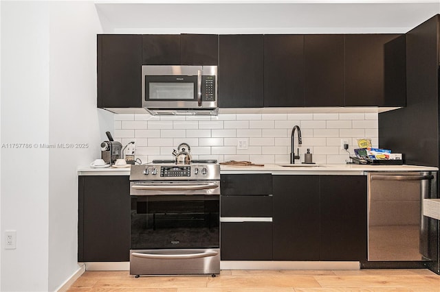 kitchen featuring appliances with stainless steel finishes, light countertops, a sink, and backsplash