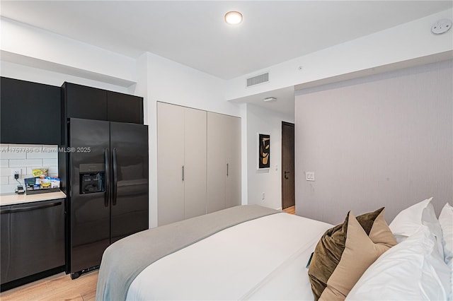 bedroom featuring black refrigerator with ice dispenser, light wood-type flooring, and visible vents