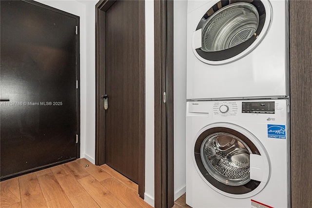 laundry area featuring stacked washing maching and dryer, laundry area, and wood finished floors