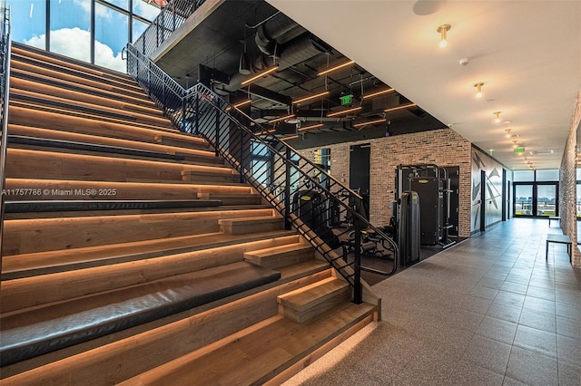 stairway featuring a healthy amount of sunlight and brick wall