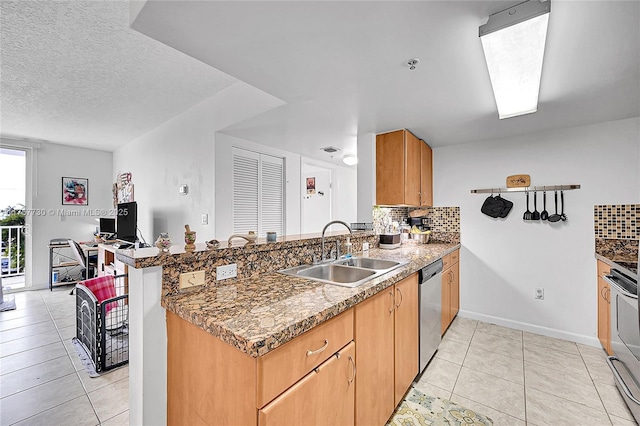 kitchen with appliances with stainless steel finishes, a sink, a peninsula, and decorative backsplash