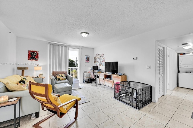 living area featuring light tile patterned floors, a textured ceiling, and stacked washer and clothes dryer