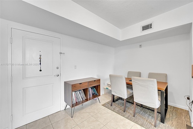 dining area with light tile patterned floors, visible vents, and a textured ceiling