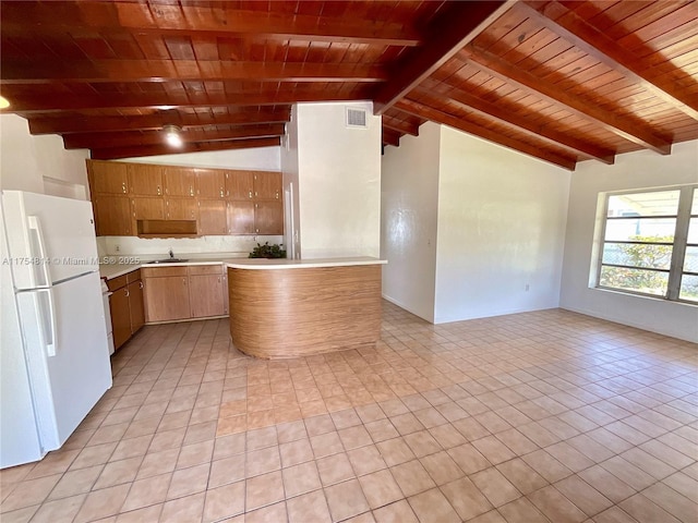 kitchen featuring vaulted ceiling with beams, visible vents, open floor plan, light countertops, and freestanding refrigerator