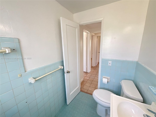 half bathroom featuring a wainscoted wall, a sink, and toilet