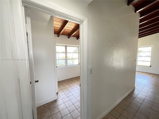 hall with a wealth of natural light, wood ceiling, tile patterned flooring, and beamed ceiling