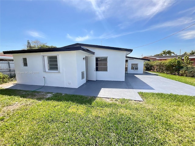 back of property with a yard, fence, a patio, and stucco siding