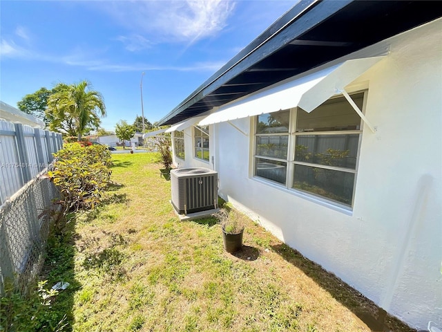 view of yard featuring central AC and fence