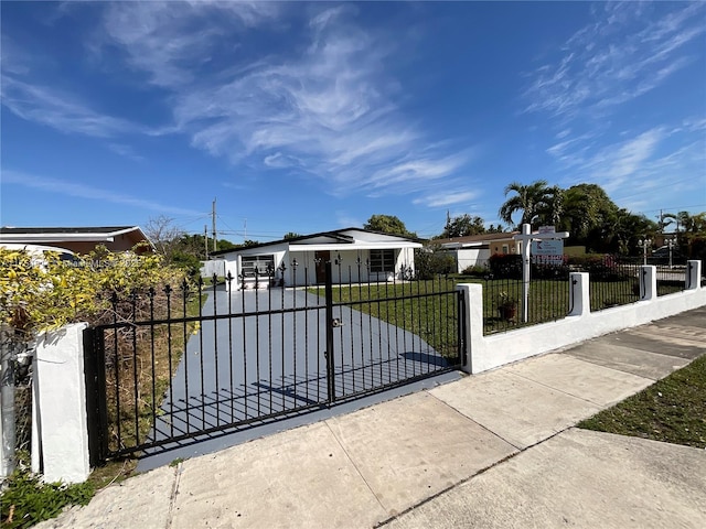 view of gate featuring a fenced front yard and a lawn