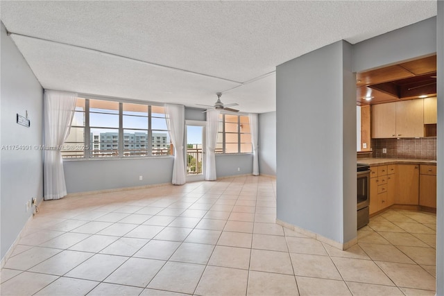 unfurnished room featuring a city view, ceiling fan, a textured ceiling, and light tile patterned floors